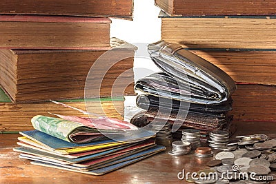 Old leather wallets and bank books with coins on wooden grunge