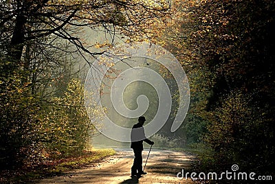 Old man in autumn forest at sunrise