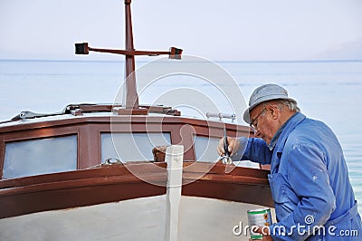 Old man painting boat