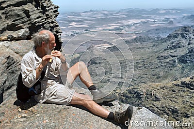Old man plays flute on top of mountain