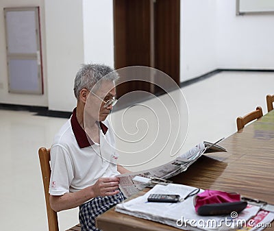 Old man reading newspaper in library