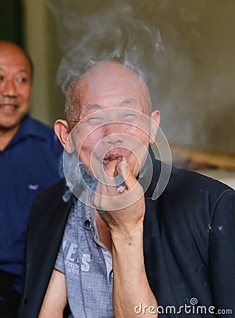 Old man smoking in gaomiao town,sichuan,china