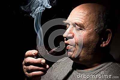 The old man smoking tobacco pipe