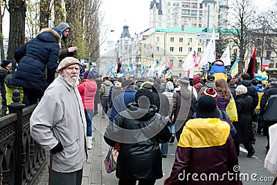 Old man watching the crowd of the walking people on anti-government demonstration during the protest