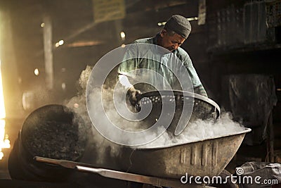 Old man working in dusty at charcoal factory