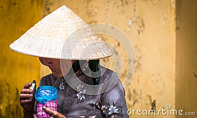 Old poor woman in conical hat holding pink jar.
