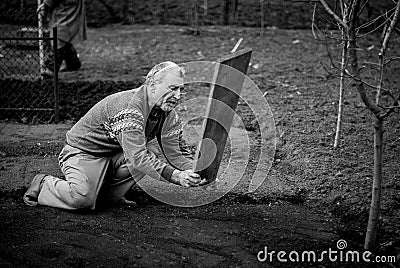 Old romanian man working his land in a traditional way with empty hands, black and white picture