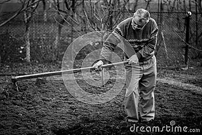 Old romanian man working his land in a traditional way with empty hands, black and white picture