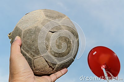 Old soccer ball in hand and red satellite background