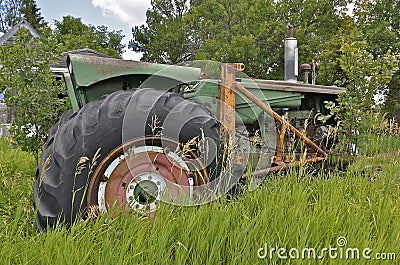 Old tractor in long grass has a loader