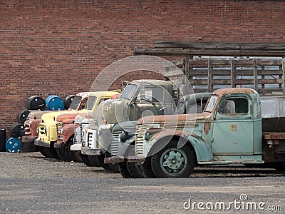 Old trucks parked against a brick wall backdrop