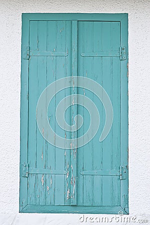 Old turquoise window made out of wood on white wall.