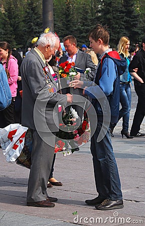 Old war veteran taking flowers from a boy