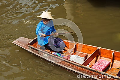Old woman paddling wooden boat