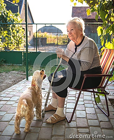 Old woman sitting on a chair with a cane