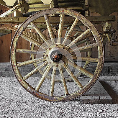 of an old wooden wagon wheel on the front end of a horse drawn wagon 