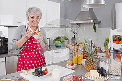 Older happy woman eating yoghurt in the morning.