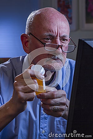 Older man looks concerned while refilling prescription online, vertical