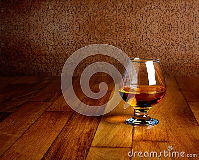 One glass of brandy on wooden counter top