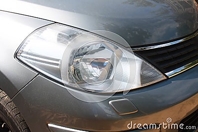 One head light gray car close-up.