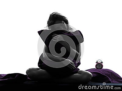 Woman sleepy hugging pillow sitting on bed silhouette