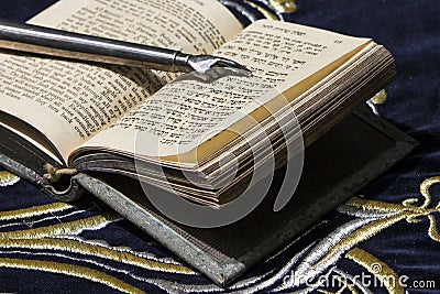 Open bible book in Hebrew with silver pointing hand