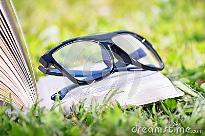 An open book with glasses on a meadow