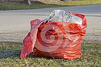 Open red plastic rubbish bag sack in park