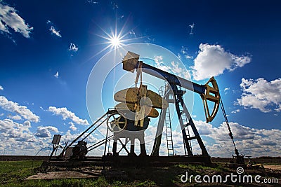 Operating oil and gas well profiled on sunny sky