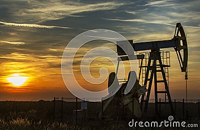 Operating oil well profiled on sunset sky