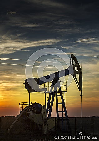 Operating oil well profiled on sunset sky