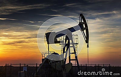 Operating oil well profiled on sunset sky