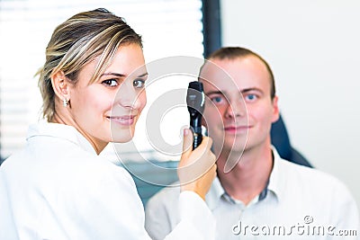 Optometry concept - handsome young man having his eyes examined