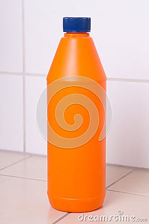 Orange plastic bottle of cleaning product on tiled floor