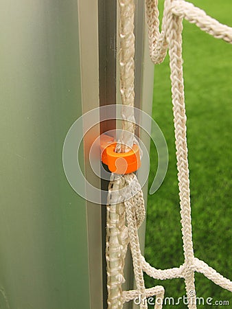 Orange plastic hanger in aluminum pole in soccer gate, soccer football net. Light green grass on football playground