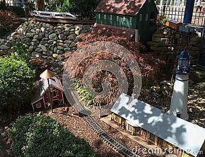 Outdoor model train track with train station lighthouse and barn