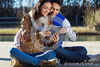 Outdoor portrait of young couple with digital tablet