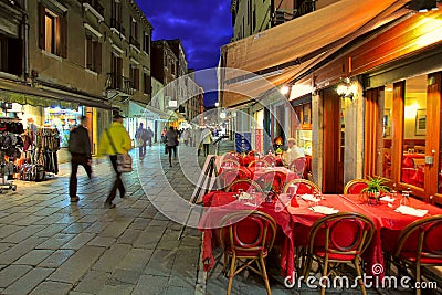 Outdoor restaurant on narrow street in Venice, Italy.
