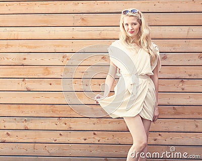 Outdoor summer sensual fashion portrait beautiful young blond woman lifts the edge of a white dress standing on the background of