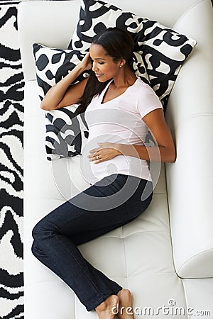 Overhead View Of Pregnant Woman Relaxing On Sofa