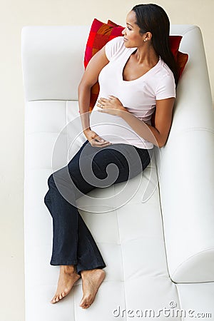 Overhead View Of Pregnant Woman Relaxing On Sofa