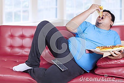 Overweight man eats pizza