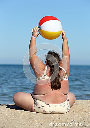 Overweight woman doing gymnastics on beach