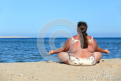 Overweightl woman meditation on beach