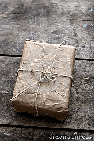 Package wrapped in wrinkled brown paper lying on weathered wood