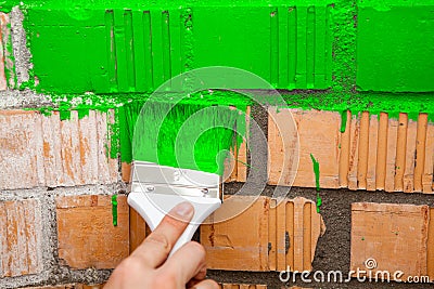 Paint brush with green color on brick wall