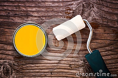 Paint roller and color tin can on wooden background