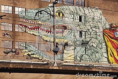 Painted lizard on and old warehouse. Train line.