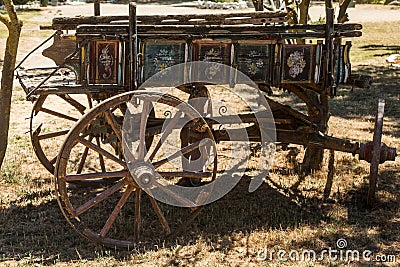 Painting antique wooden cart with big wheels on harvest.