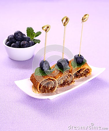 Pancake roll stuffed with minced meat on purple background